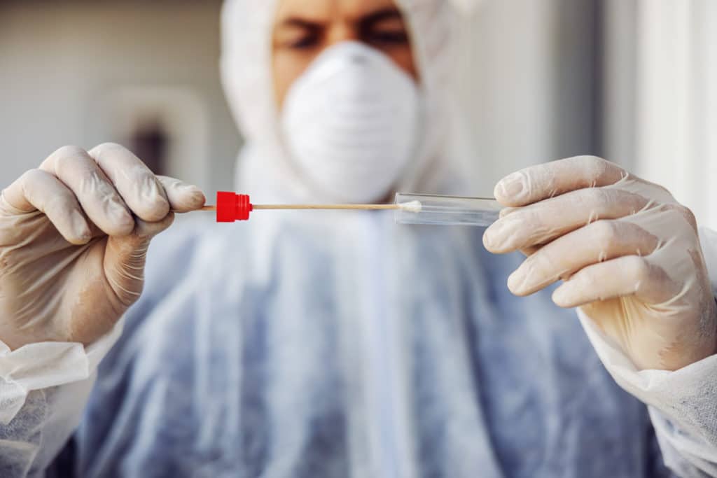 Mann in Schutzkleidung mit angenommenen Corona-Test (PCR oder Antigen-Test oder Schnelltest)